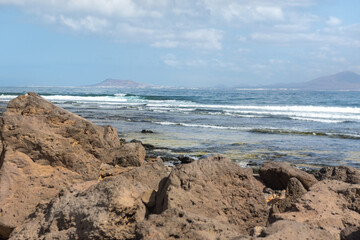 Fototapeta na wymiar Sunny day on the coast of Fuerteventura where you can see Lanzarote in the distance in the Canary Islands in Spain