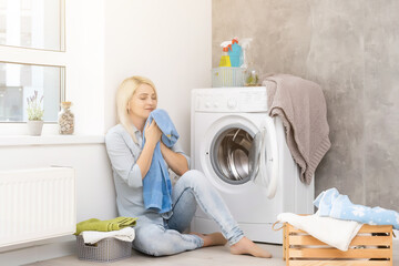 A young housewife with washing machine and clothes. Washing day.