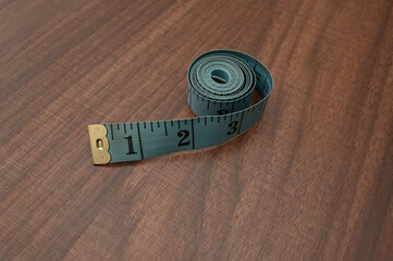 Tape measure with inch size on wooden table.