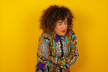Young beautiful woman wearing casual clothes over yellow background suffering from strong stomachache.