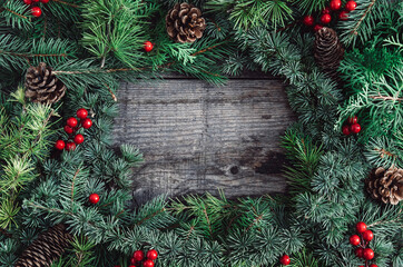 Fototapeta na wymiar Christmas fir tree branches, red berries and pinecone on wooden background stock photo