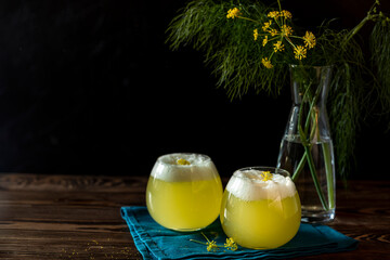 Two glasses of fennel flower cocktail with organic egg white, fennel pollen and fennel flower garnish. Scene is illuminated by beautiful evening sunlight.