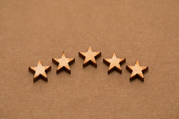 Fototapeta na wymiar Five wooden stars on cardboard background