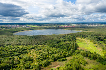 Aerial view of the countryside and a circular lake in the middle of the forest.
