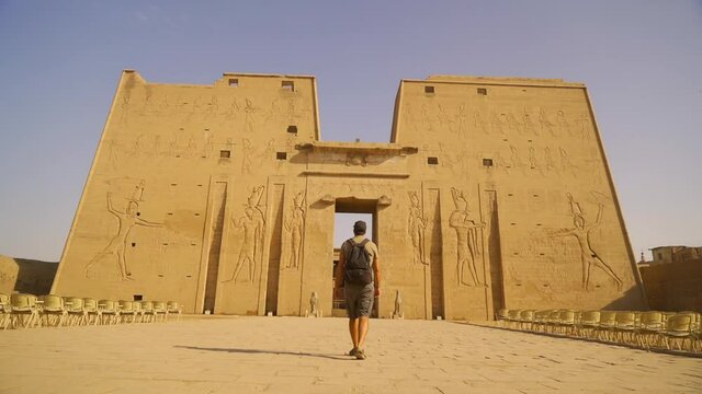 A young tourist walking towards the Edfu Temple. Egypt. River Nile in the city of Edfu near Aswan, Greco-Roman construction, dedicated to Horus