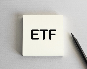 the word ETF note on a stack of paper. Grey background and marker. It can be used as a business and financial concept