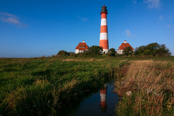 Fototapeta na wymiar Westerhever Leuchturm mit Warft an der Nordsee
