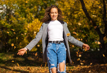 Portrait of a young blonde girl in stylish ripped jeans posing in an autumn park