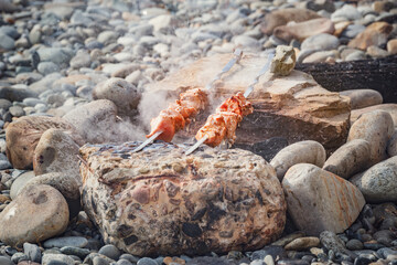 Cooking of the barbecue and sausages on the beach at evening time.