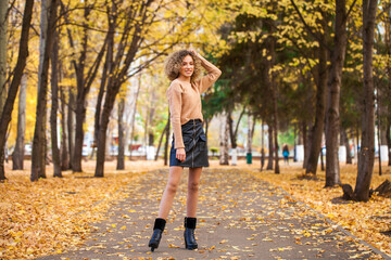 Portrait of a young beautiful girl in beige sweater and black skirt