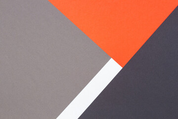 Creative abstract geometric paper background orange, white, light gray, black colors paper. Top view. Copy space