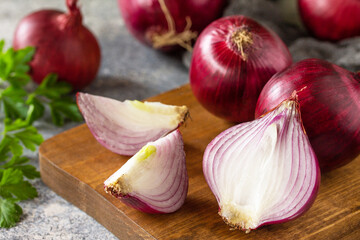 Purple Onions close-up. Fresh whole purple onions and one sliced onion on a stone countertop.