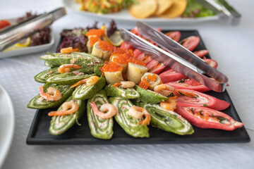 pancakes with red caviar and shrimp on a black plate