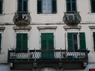 House facade with green wooden shutters and wrought-iron antique balconies