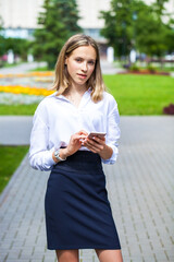 Young assistant in a white blouse phoning on the street