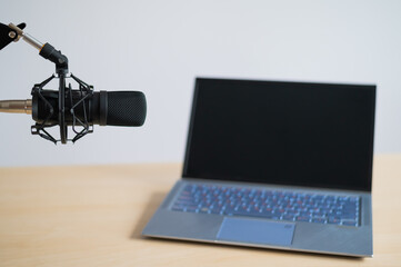 Close-up of a professional microphone on the background of a laptop. Radio broadcaster's desktop