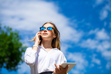 Young assistant in a white blouse phoning on the street