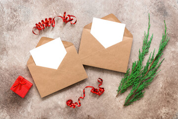 Christmas card mockup. Blank white cards in brown envelopes, fir branches, gift box and serpentine. Template for your design. Top view, flat lay.