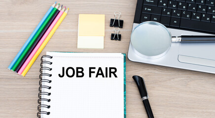 White notepad and pen on the wooden desk Job Fair Concept next to laptop.