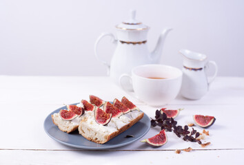 Fig and ricotta sandwich on plate and white table, breakfast
