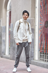 Stylish young  man wearing white  sweater and jacket standing on street