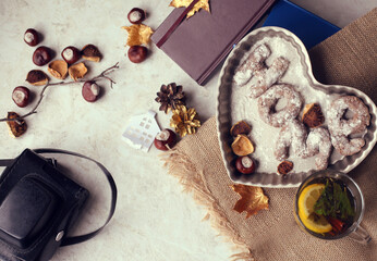 Top view of baking form in shape of heart with cookies, cup of tea, camera, notebook and chestnuts. Home concept. Copy space.
