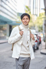 Stylish man walking down the street wearing white  sweater and jacket laughing on street