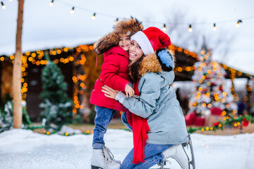 Portrait of a girl in Russian cap posing with her mom on the ice rink.