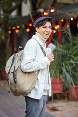 Stylish man walking down the street wearing white  sweater and jacket laughing on street