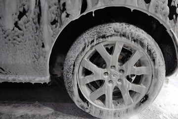 Fototapeta na wymiar car wheel is covered with soapy foam