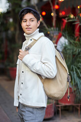 Stylish man walking down the street wearing white  sweater and jacket on street