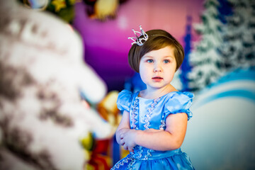 a small ,beautiful girl in a Princess carnival dress,standing near the scenery in the new year's holiday