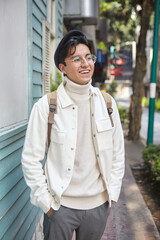 Stylish man walking down the street wearing white  sweater and jacket laughing on street