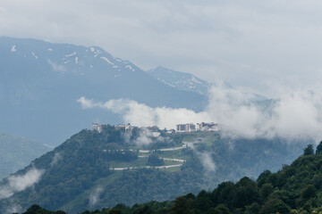 The beautiful landscape of the city among the mountains shrouded in mist and clouds. Nature of Europe in cold colors.