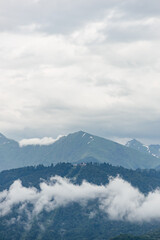 Fototapeta na wymiar Beautiful landscape of mountain peaks shrouded in clouds. Nature of Europe in cold colors.