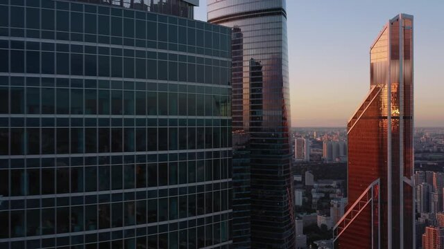 Moscow city glass skyscrapers drone zoom out, flying back, setting sun reflection in the windows. Moscow International Business Center at the sunset, cityscape horizon at the evening