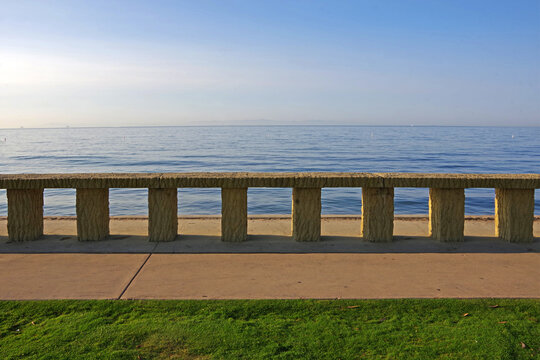 Sidewalk with stone guard rail along the Pacific ocean at Butterfly Beach in Montecito, California, on a sunny autumn morning