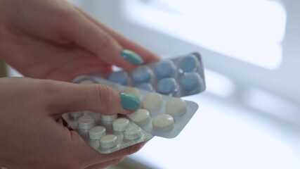 The girl is sorting through the blue and white tablets in package in her hands.