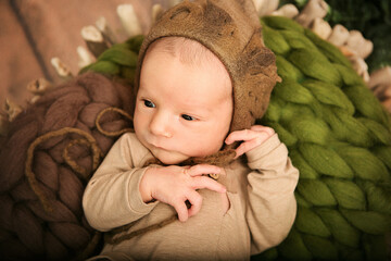 a newborn boy 12 days old in an elf kitten lies in a basket

