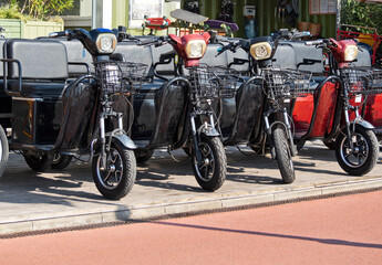 Row of electric scooters with seats in rental station outdoors