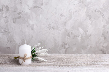Fototapeta na wymiar mock up of a white candle wrapped in jute with a sprig of Muscari on a wooden table.