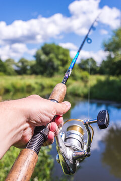 Male hand holding a fishing rod/Male hand holding a fishing rod from the first person. On a sunny day