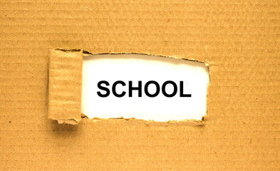 The word School appearing behind torn brown paper