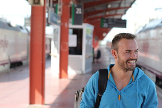 Blonde man smiling in train station
