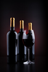 wine bottles and full glass with red and black background