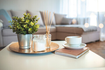 Hygge and aromatherapy concept - Coffee, candles, book and aroma reed diffuser on table at home. Home fragrance in sticks. Air freshener, diffuser and aromatherapy concept