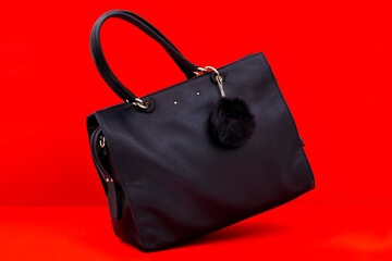 Black lady bag over red background in a studio shot.