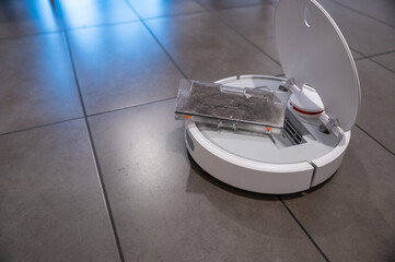 House scenes: house cleaning, the robot vacuum cleaner has a tank full of dirt: it has been...