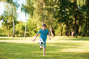 Young boy is playing soccer in park