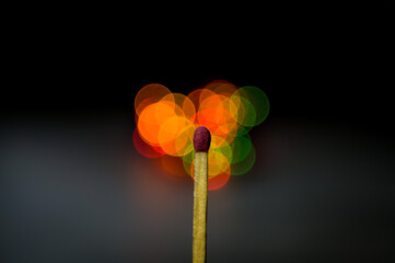 The match burns with blurred lights in the background